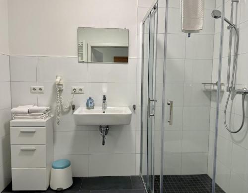 a white bathroom with a sink and a shower at Stilvoll Wohnen in Oldenburg Kreyenbrück Apartments in Oldenburg