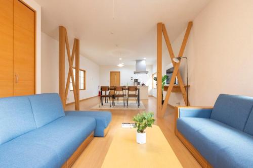 Una sala de estar con dos sofás azules y una mesa. en アブラハウス別府, en Beppu