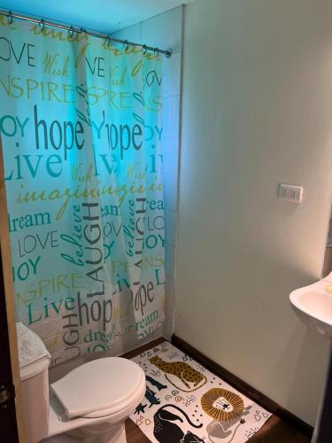 a bathroom with a shower curtain with writing on it at Cabañas Vista Volcanes I in Puerto Varas