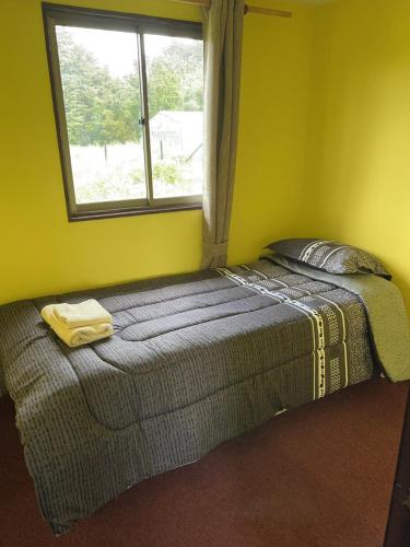 Bett in einem Zimmer mit Fenster in der Unterkunft Cabañas Vista Volcanes I in Puerto Varas