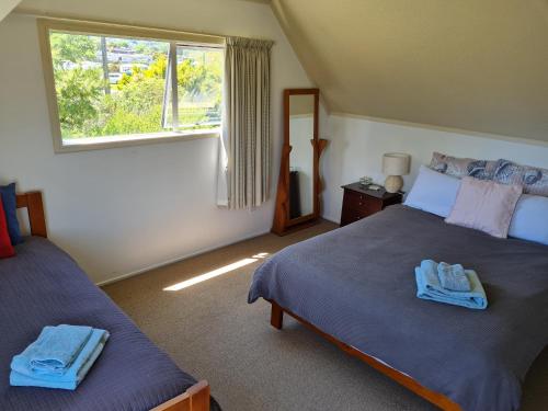 sypialnia z 2 łóżkami i oknem w obiekcie Seaside Tahuna w mieście Nelson