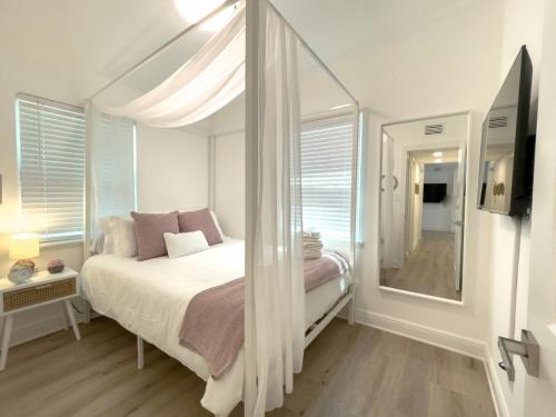 a white bedroom with a bed and a mirror at Calming And Renovated Near Dt St Pete Pier 2 King in St Petersburg