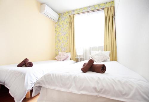 two white beds in a room with a window at Ustay Kitakoiwa in Tokyo