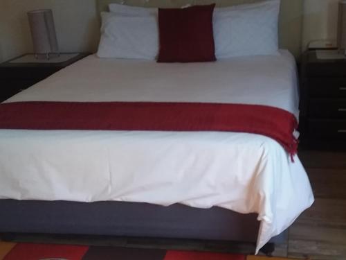 a large bed with white sheets and a red blanket at Cheryl's Fortress in Johannesburg