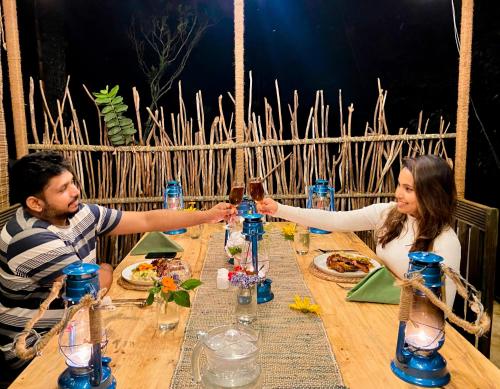 a man and woman sitting at a table with drinks at Eco Wild Glamping Bambarakanda 