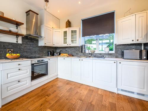 a kitchen with white cabinets and a wooden floor at Low Bank in Lancaster