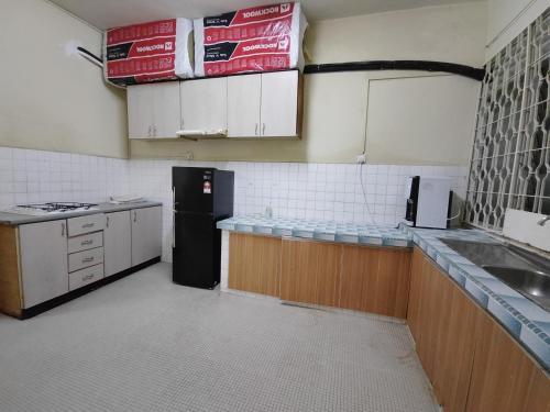 Il comprend une cuisine équipée d'un réfrigérateur noir et de placards blancs. dans l'établissement GP Hostel Penang, à George Town