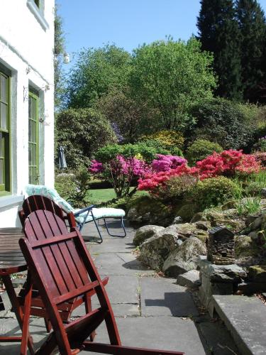 two wooden chairs sitting on a patio next to a garden at Foxghyll Country House in Ambleside