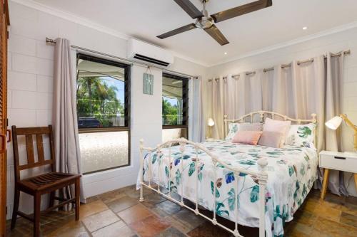 Schlafzimmer mit einem Bett, einem Stuhl und Fenstern in der Unterkunft Tranquil 3BR King Home, Pool, BBQ in Trinity Beach