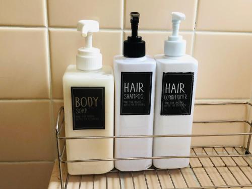 three bottles of shampoo and conditioner sitting on a rack in a bathroom at 一軒家貸切いすみベース in Chōjamachi