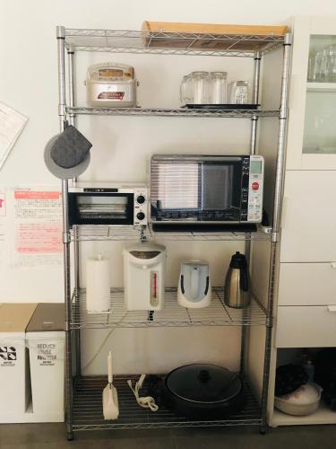 a kitchen shelving unit with a microwave and other appliances at 一軒家貸切いすみベース in Chōjamachi