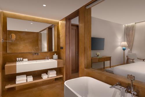 a bathroom with a bed and a tub and a sink at Time Square Resort & Spa Bhuj in Bhuj