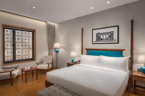 a bedroom with a large white bed and a chair at Time Square Club, Resort & Spa in Bhuj