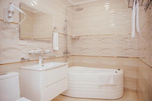 a white bathroom with a toilet and a sink at al Madina Hotel Samarkand in Samarkand