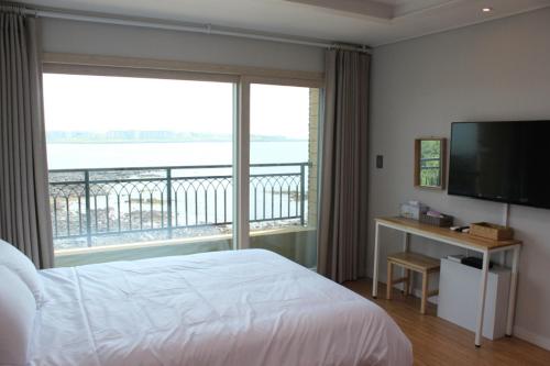 a hotel room with a bed and a large window at Haemorat Pension in Seogwipo
