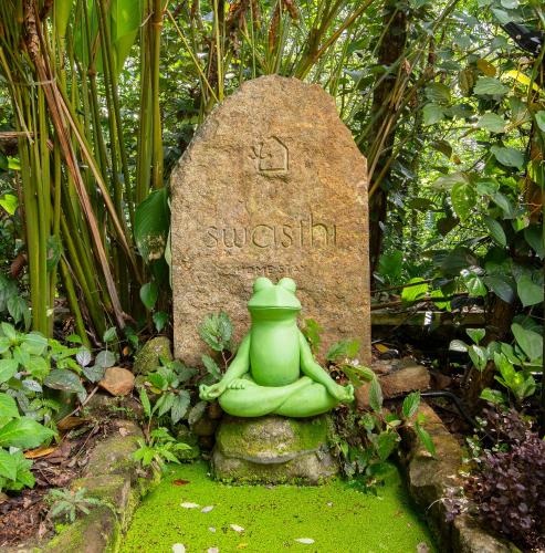 a statue of a green frog sitting on a gravestone at Swasthi Serviced Villa in Kanjirapalli