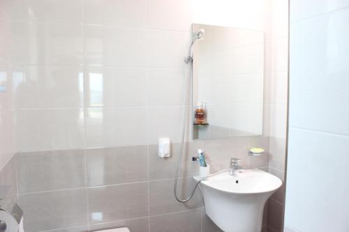 a white bathroom with a sink and a mirror at Haemorat Pension in Seogwipo