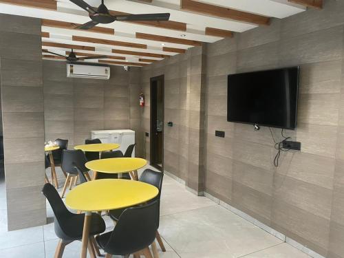 Habitación con mesas y TV de pantalla plana en la pared. en Stay10 Studio Apartments en Indore