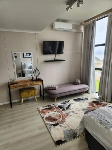 a bedroom with a couch and a tv on the wall at 13 at Santos in Mossel Bay