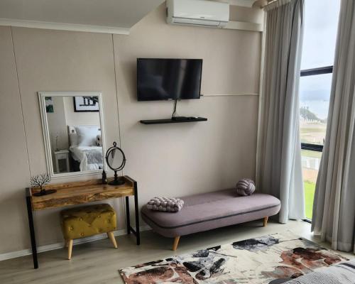 a living room with a tv and a bench and a mirror at 13 at Santos in Mossel Bay