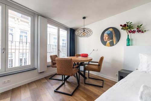 Stylish apartments in the heart of Breda city center في بريدا: غرفة طعام مع طاولة وكراسي وسرير