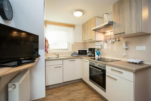 a small kitchen with white cabinets and a television at Apartment Žvan in Bohinj