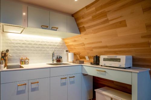 a kitchen with white cabinets and wooden walls at A-Frame House Minami Karuizawa - Vacation STAY 58046v in Karuizawa
