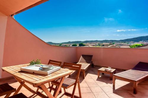 un balcone con tavoli e sedie in legno e una grande finestra di Apartments with swimming pool in Santa Teresa di Gallura a Santa Teresa di Gallura