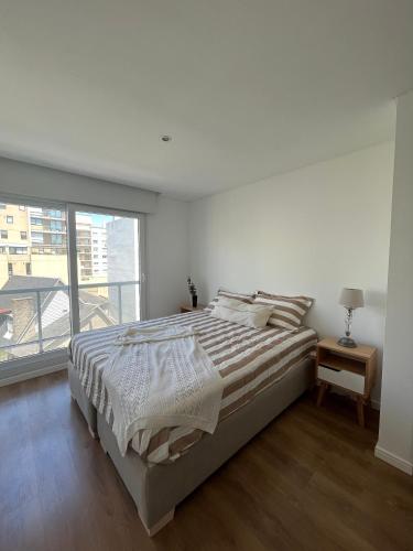 a white bedroom with a large bed and a window at Roca Trust II Semipiso de 3 ambientes para 4 personas en zona güemes con cochera in Mar del Plata