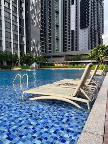two lounge chairs in a swimming pool with tall buildings at Millerz Suite 3R2B Condo Near MidValley 3 Beds 3 Bedrooms Staycation Best Choice in Kuala Lumpur