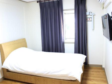a bed in a room with a window and a bed frame at The Lucete Hotel in Seogwipo