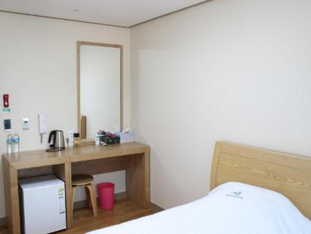 a bedroom with a desk with a bed and a mirror at The Lucete Hotel in Seogwipo