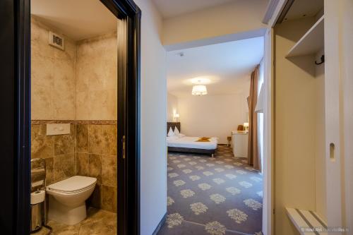 a bathroom with a toilet and a bedroom at Hotel Aldi in Gura Humorului
