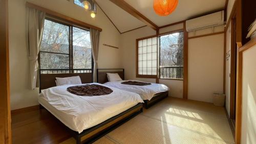忍野村的住宿－shinka Lake Yamanaka - Vacation STAY 11008v，一间卧室设有两张床和两个窗户。