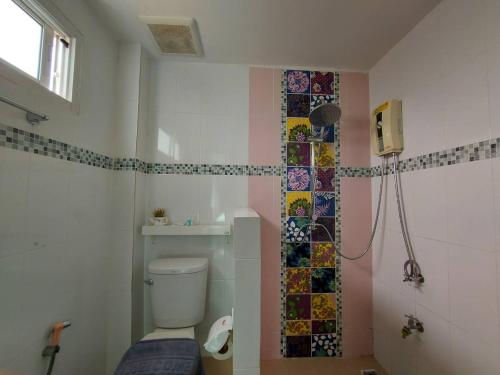 ein Bad mit einem WC und einer Dusche mit Mosaikfliesen in der Unterkunft Graphic House @ Chiang Rai in Chiang Rai