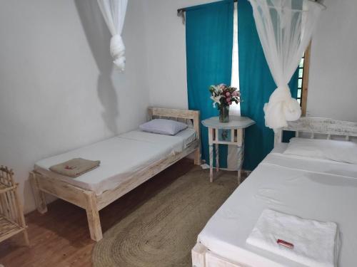 a room with two beds and a table with flowers at Sunny garden rooms Watamu in Watamu
