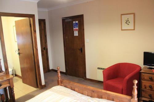 a bedroom with a red chair and a television at Craignure Inn in Craignure