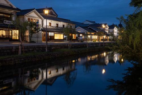 仓敷滔々 日本郷土玩具館 蔵の宿 toutou, Gangukan Kura no Yado的夜晚的城市，有河流和建筑物