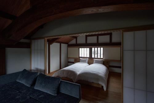 倉敷的住宿－滔々 日本郷土玩具館 蔵の宿 toutou, Gangukan Kura no Yado，一间卧室配有一张大床和一张沙发
