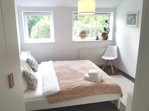 a white bedroom with a bed and two windows at Stedinger Landhotel & Café in Berne