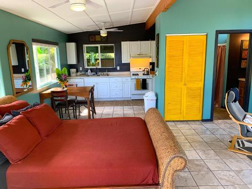 a living room with a red couch and a kitchen at Puna Pod in Pahoa