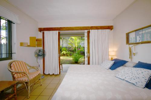 a bedroom with a bed and a desk and a chair at Villa Cap Malheureux in Cap Malheureux