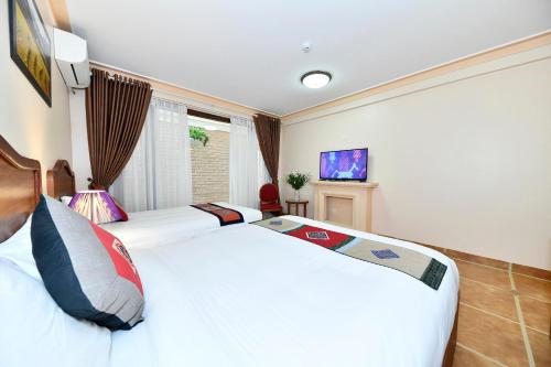 een slaapkamer met 2 bedden en een televisie bij Sapa Symphony Hotel in Sa Pa