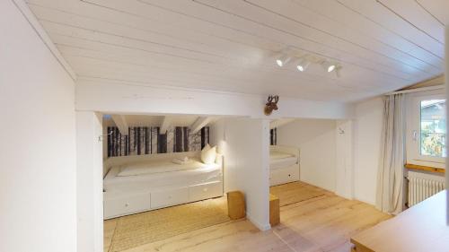 a white room with two beds and a window at Ski in-Ski out Apartment Luscheina-Lenzerheide in Valbella