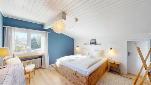 1 dormitorio con 1 cama grande y pared azul en Ski in-Ski out Apartment Luscheina-Lenzerheide, en Valbella