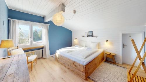a bedroom with a large bed and a blue wall at Ski in-Ski out Apartment Luscheina-Lenzerheide in Valbella