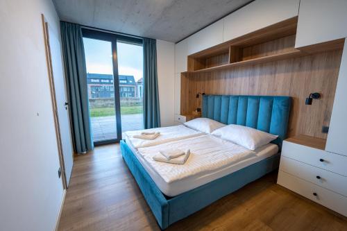 a bedroom with a blue bed and a large window at Vila Jestřábí s výhledem na Lipno, klidná lokalita in Černá v Pošumaví