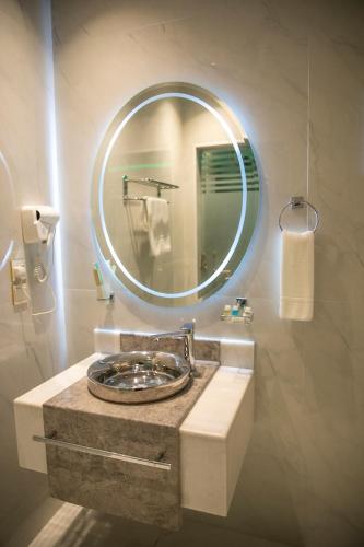 a bathroom with a sink with a round mirror at فندق روند in Hafr Al Baten