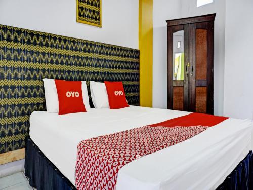um quarto com uma cama com almofadas vermelhas e brancas em OYO 91796 Guest House Ghalta Syariah em Karawang