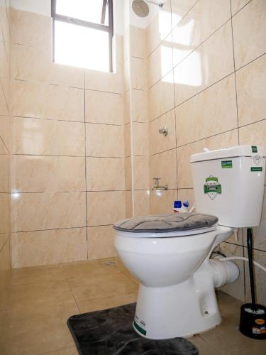 a white toilet in a bathroom with a window at Lux Suites Casey's Apartments Bamburi in Bamburi